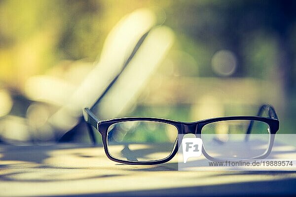 Schwarze Brille und Buch draußen im Park  Sommerzeit