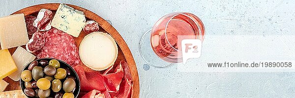 Charcuterie und Käse Panoramabanner  aufgenommen von oben mit einem Glas Roséwein. Prosciutto di Parmaschinken Blauschimmelkäse  Oliven und Cracker  Gourmet Antipasti mit Kopierraum