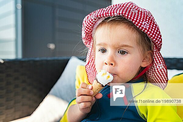Portrait kleines Kind mit großen Augen leckt Eis im Sommer. 2 Jahre altes Baby Mädchen. Kinder essen Süßigkeiten
