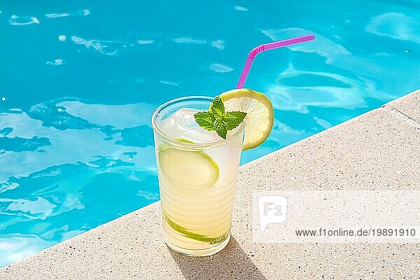 Frische Limonade oder Mojitococktail im Glas mit Strohhalm am Rande einer Schwimmhalle an einem sonnigen Tag