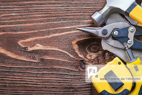 Hammer Schutzhandschuh Maßband Schraubenzieher und Zange auf Holzbrett
