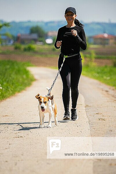 Mädchen läuft mit Hund draußen in der Natur auf einer Landstraße Sonniger Tag auf dem Lande mit Beagle Hund