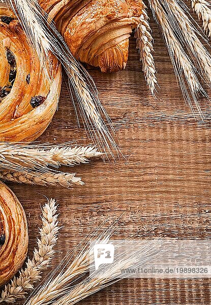 Goldene Weizenohren Rosinenbrötchen Croissant auf Eichenholzbrett Essen und Trinken Konzept