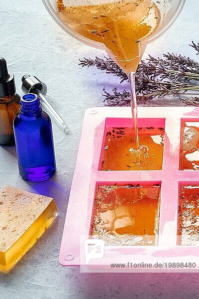 Handgemachte Seife  der Prozess der Herstellung. Natürliche Biokosmetik mit Lavendelblüten und ätherischen Ölen. Glycerin in eine Form gegossen