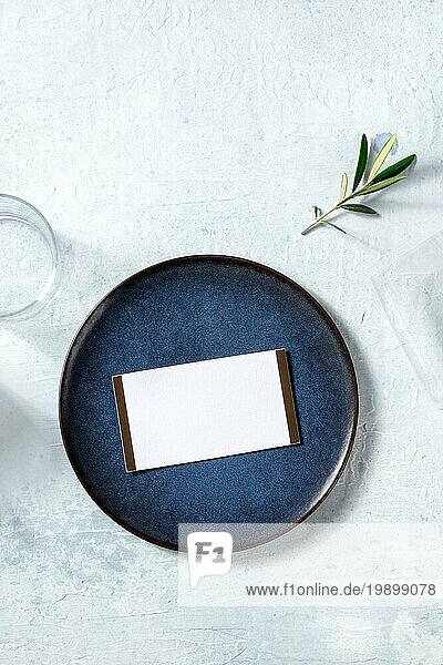 Abendessen Einladung Mockup  Schuss von oben auf einen blaün Teller mit einem Olivenzweig. Mediterrane Küche Restaurant RSVP Karte
