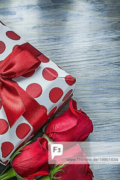 Geschenkbox mit Knoten erweitert rote Rosen auf Holzbrett Urlaub Konzept