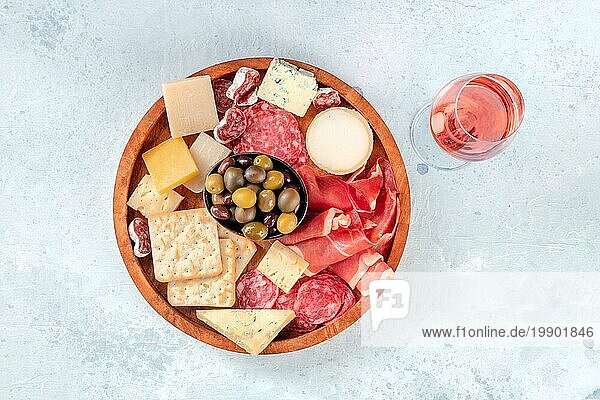 Charcuterie und Käseplatte  von oben fotografiert  mit einem Glas Roséwein. Prosciutto di Parmaschinken Blauschimmelkäse  Oliven und Cracker  Gourmet Antipasti