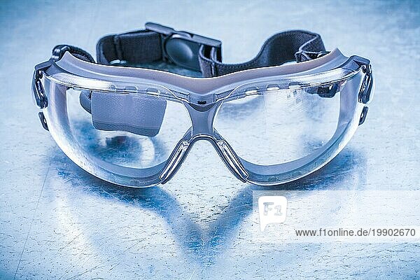 Transparente Kunststoff Schutzbrille auf metallischem Hintergrund Konstruktionskonzept