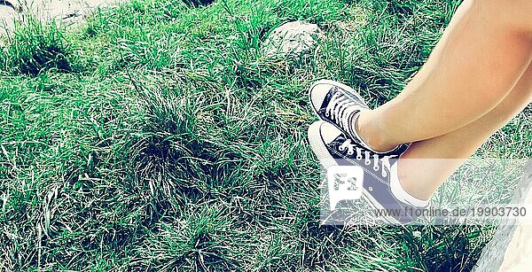 Schwarze Turnschuhe und grünes Gras im Sommer: freie Zeit für Teenager