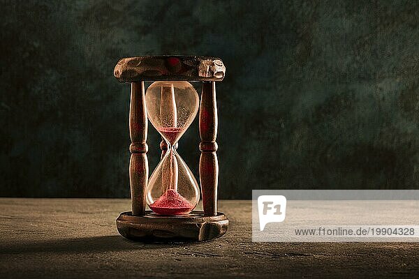 Die Zeit läuft aus Konzept. Eine Sanduhr mit Sand fallen durch  auf einem dunklen Hintergrund mit einem Platz für Text  getönten Bild