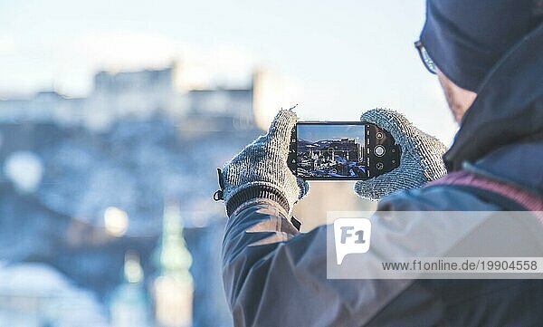 Junger Tourist macht ein Foto von Salzburg mit ihrem Smartphone  Winterzeit