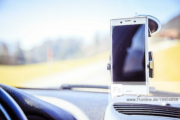 Innenraum eines modernen Autos an einem sonnigen Tag. Smartphone auf mobiler Halterung  verwendet als Navigationsgerät