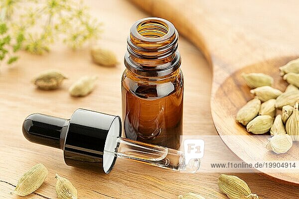 Ätherisches Kardamomöl in einer Flasche auf einem Holztisch. Alternative Medizin
