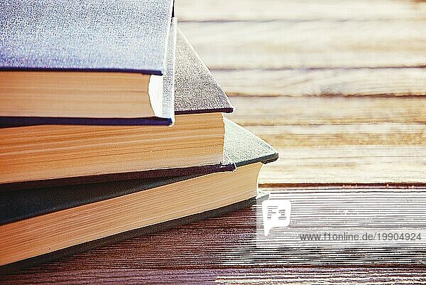 Stapel von drei alten Büchern im Gegenlicht auf Holztisch  selektiver Fokus