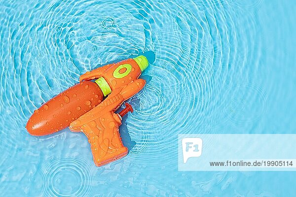 Wasserpistole Spielzeug auf blaün Wasseroberfläche mit gekräuselten Wellen. Spaß  Freizeit Sommerzeit Hintergrund. Raum kopieren
