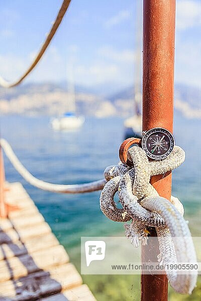 Kompass auf einem Segelseil liegend  Meer und Segelboote im unscharfen Hintergrund
