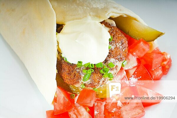 Frischer traditioneller Falafel Wrap auf Fladenbrot mit frischen gehackten Tomaten  Food photography