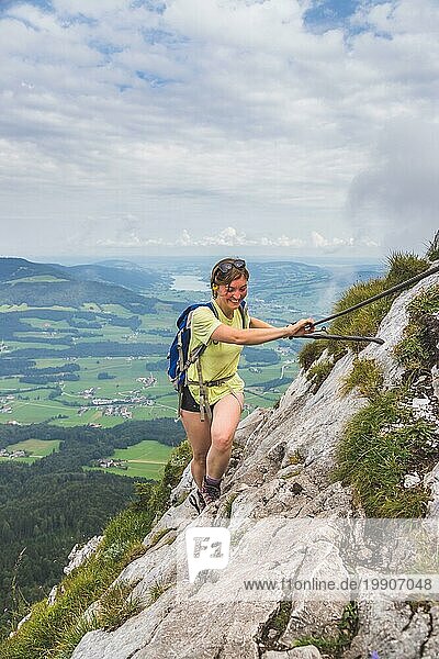Junges schlankes Rucksacktouristenmädchen beim Klettern auf einem felsigen Berg  Österreich  Europa