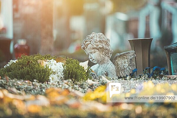 Weißer Engel auf einem Grab auf einem Friedhof  Blumen
