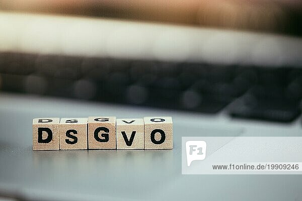 Holzwürfel mit den Buchstaben DGSVO für Datenschutzgrundverordnung liegen auf einem Laptop