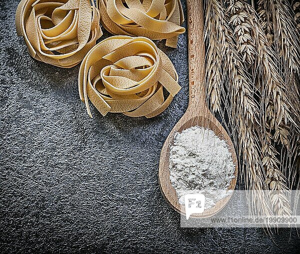 Reifer Weizen Roggen Ohren Holzlöffel Mehl ungekochte Nudeln auf schwarzem Hintergrund Essen und Trinken Konzept