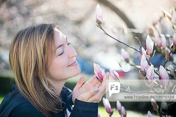 Schönes Mädchen riecht an Magnolienblüten im Frühling  Salzburg  Schönheit