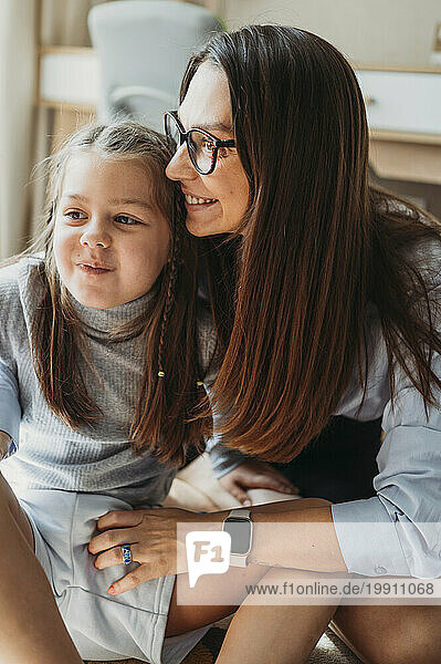 Loving mother sitting with daughter at home