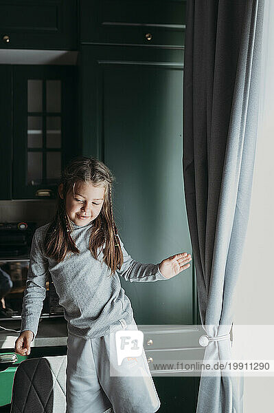 Smiling girl dancing in kitchen at home