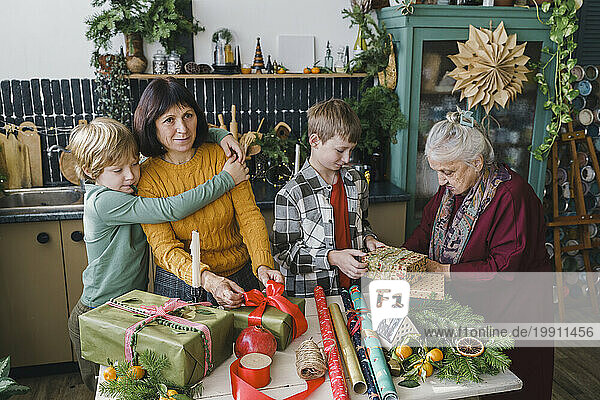 Family helping each other packing Christmas gifts at home