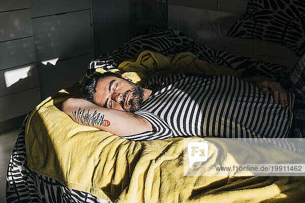 Man sleeping with sunlight on bed at home