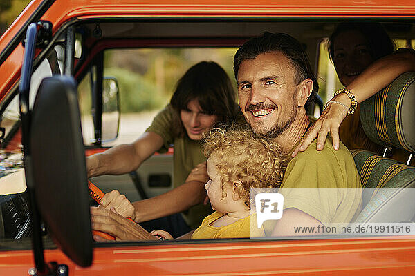 Happy man with family sitting in motor home during vacation