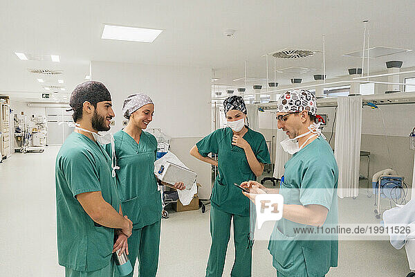 Surgeon using smart phone having discussion with colleagues in hospital