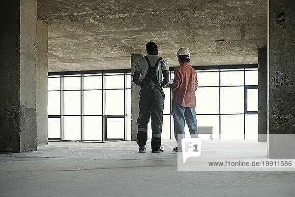 Engineer having discussion with construction worker at site