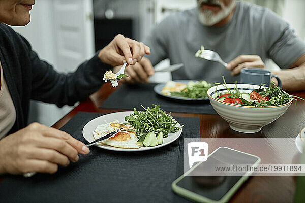 Couple eating fried eggs and salad for breakfast at home