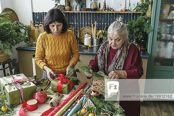 Senior woman packing Christmas gifts with mother at home
