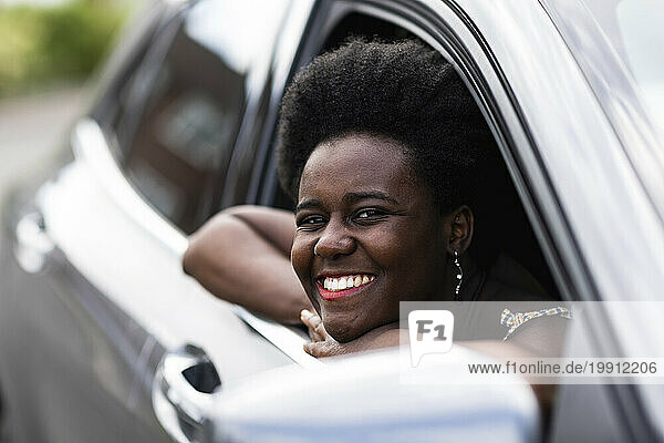 Smiling woman leaning on window of car