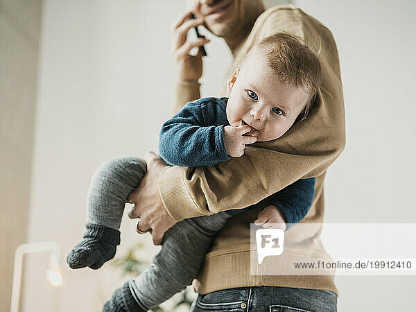 Cute baby boy with man talking on smart phone