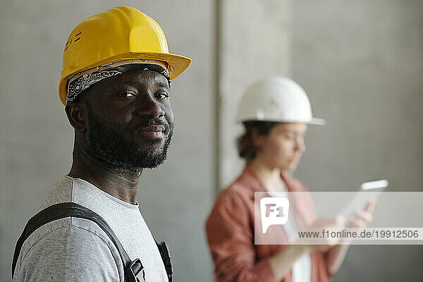 Construction worker wearing hardhat with engineer in background