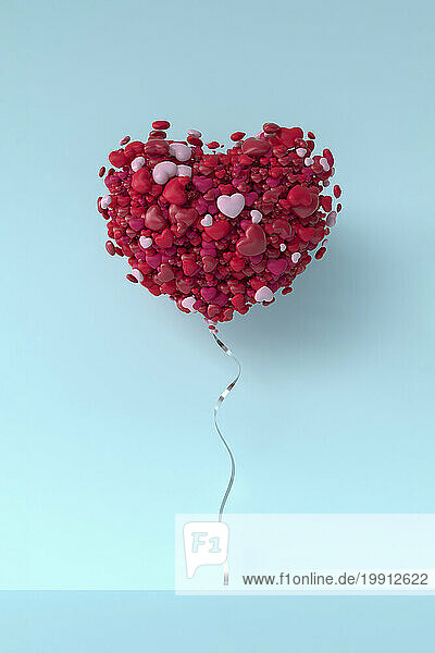 Balloon made from bunch of hearts levitating against blue background