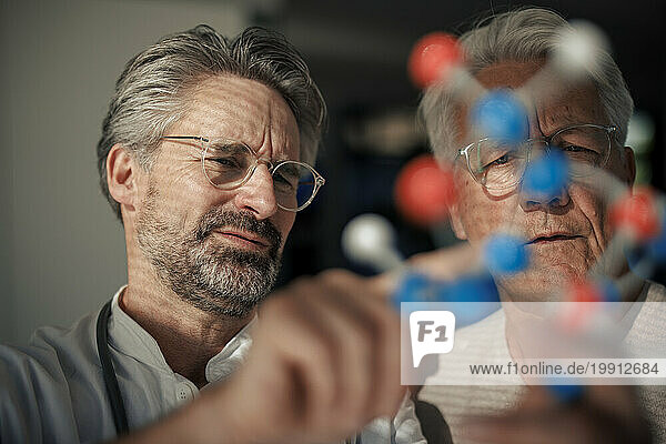 Senior scientist discussing with man over molecular structure