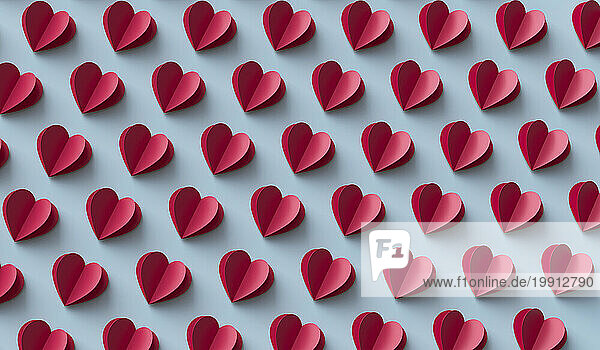 Red paper hearts arranged over blue background