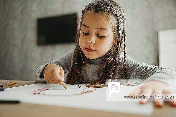 Girl with braided hair drawing with crayon at home