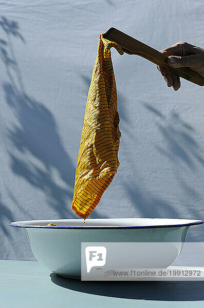 Hand of person dyeing towel in enamel bowl