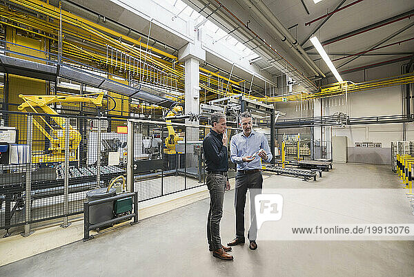 Businessmen planning in front of machinery at factory