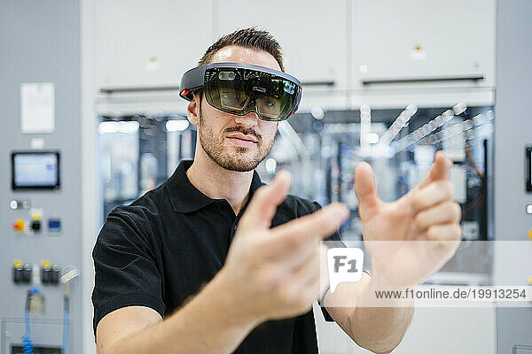 Technician wearing augmented reality glasses and gesturing in a factory