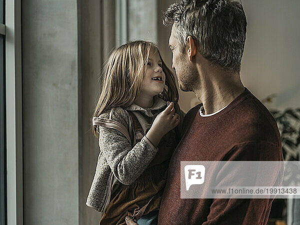 Mature man carrying daughter in arms at home
