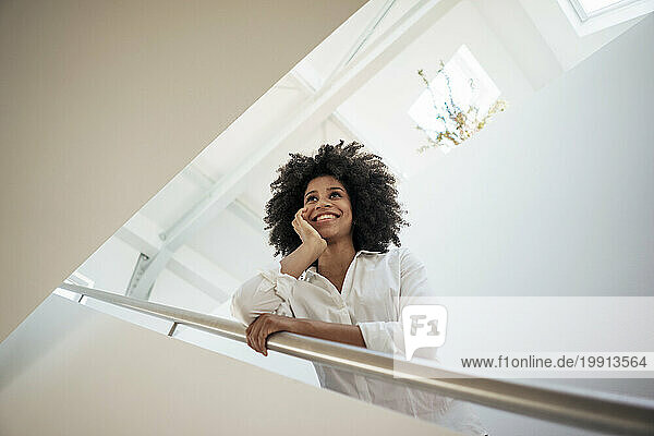 Smiling businesswoman leaning on railing at work place