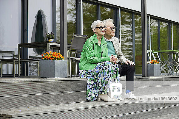 Senior couple sitting on steps in front of their home