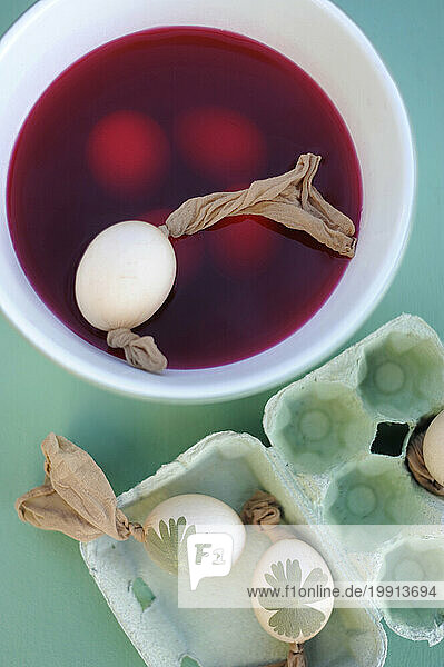 Easter eggs dyeing in bowl with red dye