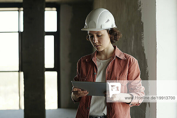 Engineer wearing hardhat and using tablet PC at construction site